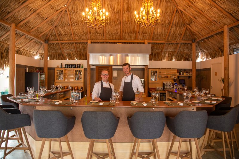 Image of the two chefs from 'Chefs Restaurant' proudly posing in front of their bar, showcasing the establishment known for its exclusive chef's table dining experience on Bonaire.