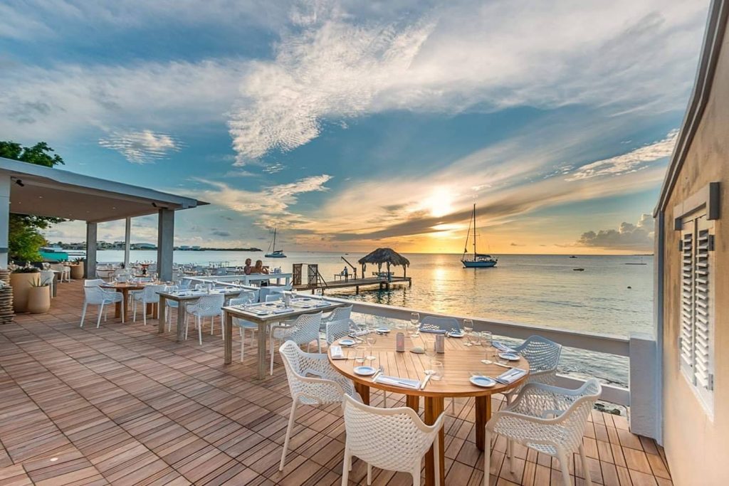 Image of 'Sebastian's Restaurant' during sunset, with the warm hues of the setting sun casting a golden glow over the establishment on Bonaire.