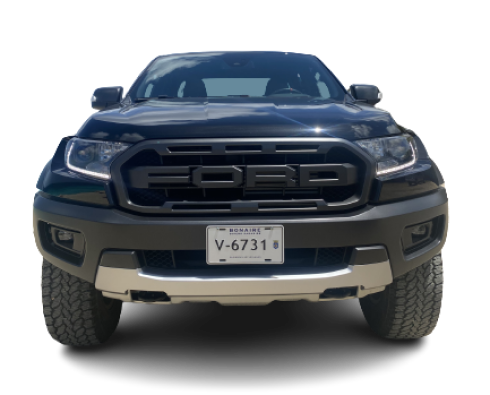 Imposing front view of the Ford Raptor, showcasing its bold grille, piercing headlights, and commanding road presence.
