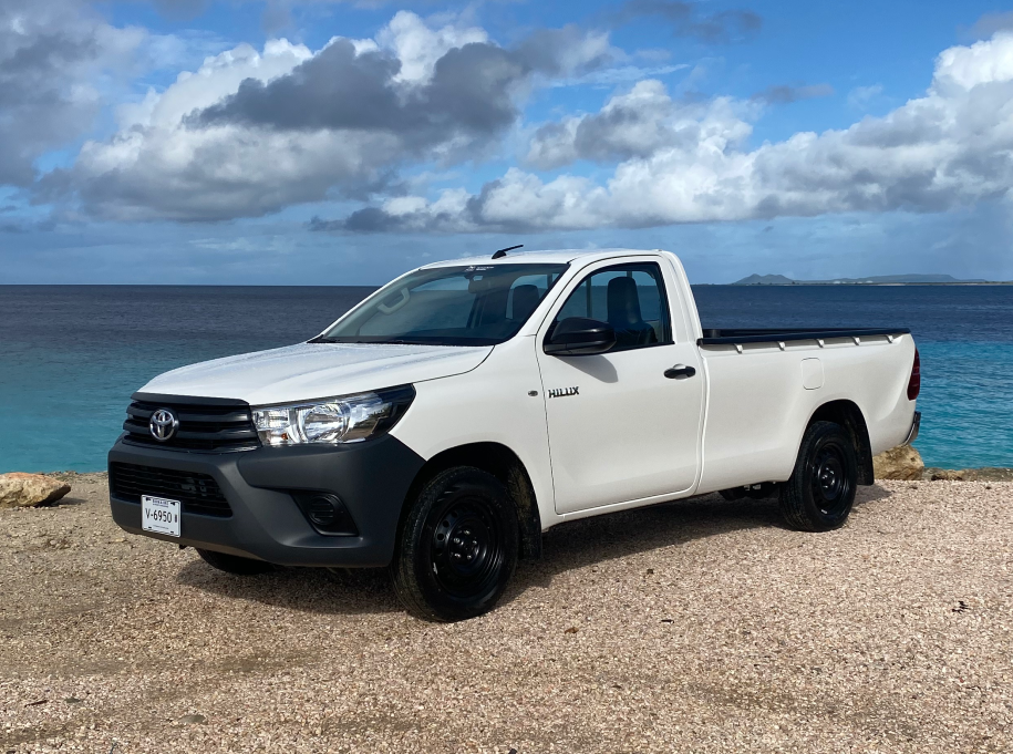 Toyota hilux Single Cabin Lowdeck from the Pickup Rental Bonaire fleet, prominently showcased against the backdrop of Bonaire's crystal blue waters.