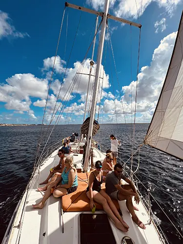 Groep mensen die genieten van een zeiltocht op het serene water van Bonaire. Huur een boot of boek een zeiltocht bij onze partner en geniet van speciale kortingen op pick-up verhuur bij Pickup Huren Bonaire.